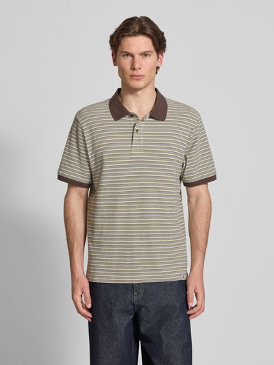 Männermodel trägt Regular Fit Poloshirt mit Label-Detail Modell 'Dion' von Carhartt Work In Progress, Reine Baumwolle, Allover-Look, Knopfleiste, Rückenlänge bei Größe M 71 cm, Ganzkörperansicht von vorne.