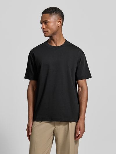 Männermodel trägt Relaxed Fit T-Shirt aus reiner Baumwolle von Marc O'Polo, unifarben schwarz, Rundhals, Feinripp, Ganzkörperansicht von vorne.