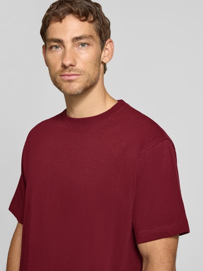 Männermodel trägt Relaxed Fit T-Shirt aus reiner Baumwolle Modell 'MAARKOS HEAVY WEIGHT' von ARMEDANGELS in Dunkelrot, Nahaufnahme Oberkörper, Herren T-Shirt von ARMEDANGELS.