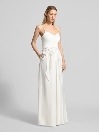 Modelka kobieca ma na sobie Jumpsuit mit Wasserfall-Ausschnitt und Spaghettiträgern od Hey Kyla z satyny, taliowany fason, lejący dekolt, cienkie ramiączka, wiązany pasek, zapięcie na haftkę i zamek błyskawiczny z tyłu, długość tyłu w rozmiarze 36: 39 cm, szerokość w rozmiarze 36: 33 cm, całkowita długość w rozmiarze 36: 154 cm, długość wewnętrzna nogawki: 84 cm, jasny kolor, gładka satynowa powierzchnia, pełny widok z przodu.