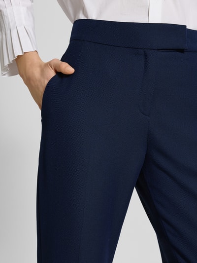 Vrouwenmodel draagt stoffen broek met structuurpatroon Model 'Hilesa' van HUGO, persplooien, steekzakken, recht model, detailopname heup.