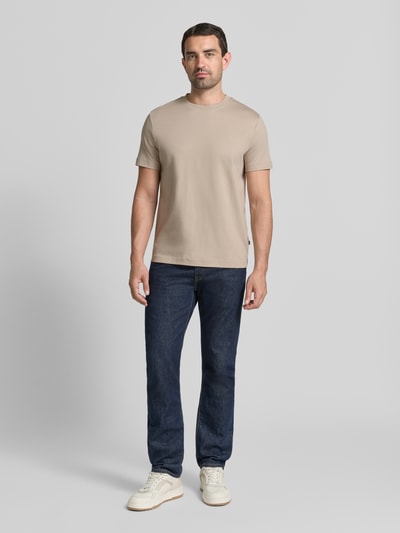 Męski model nosi T-Shirt mit Rundhalsausschnitt und Logo-Stitching von JOOP!, beżowy, bawełna, krój regular fit, kolekcja, okrągły dekolt, wyhaftowane logo, Długość tyłu w rozmiarze M: 68 cm, Ganzkörperansicht von vorne.
