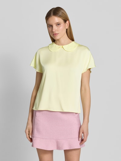 Modelka nosi Blusenshirt aus Satin mit Umlegekragen od Marc Cain, satynowy materiał, jasny żółty kolor, krój regular fit, zapięcie z tyłu na guzik, długość tyłu w rozmiarze 36: 59 cm, długość rękawa w rozmiarze 36: 20 cm, widok całej sylwetki z przodu.