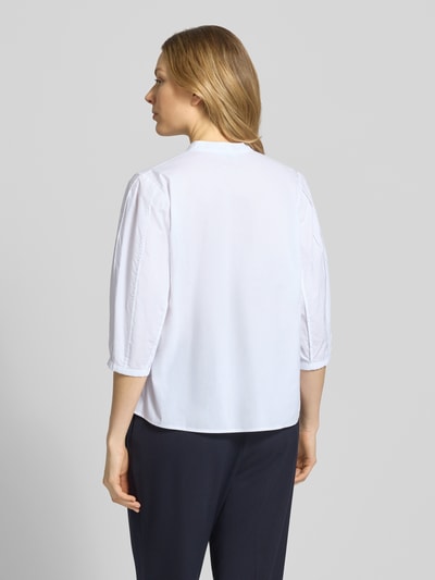 Modelka kobieca ma na sobie Bluse mit Serafino-Ausschnitt und Keulenarm von Christian Berg Woman Selection, biała bawełna, krój loose fit, widok całej sylwetki z tyłu.