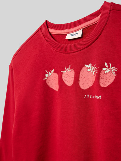 Mädchen trägt Regular Fit Sweatshirt aus Baumwoll-Mix Modell 'GEORGIA LIFE' von Only, Optik: Unifarben, Motiv-Print Erdbeeren, Crew Neck, Langarm, gerippte Abschlüsse, Sweat, Materialverarbeitung: Baumwoll-Mix, Nahaufnahme Oberkörper.