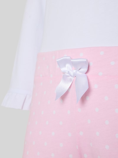 Frauenmodel trägt Pyjama aus reiner Baumwolle Modell 'Lieblingshase' von LOUIS & LOUISA mit Zierschleife, Nahaufnahme Oberkörper.