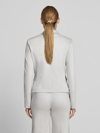 Frauenmodel trägt Slim Fit Blazer mit Pattentaschen von Marc Cain, Material-Mix mit Baumwoll-Anteil, Farbe hellgrau, Ganzkörperansicht Rückansicht. Rückenlänge bei Größe 36: 54 cm, Brustweite 35 cm, Ärmellänge 63 cm, Reverskragen, Knopfverschluss.