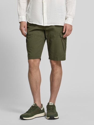 Męski model nosi Relaxed Fit Cargoshorts aus reiner Baumwolle Modell 'FILE' od s.Oliver RED LABEL, oliwkowy kolor, gładka struktura, kieszenie boczne, tylne i cargo, bawełna; widok na całe ciało z przodu.