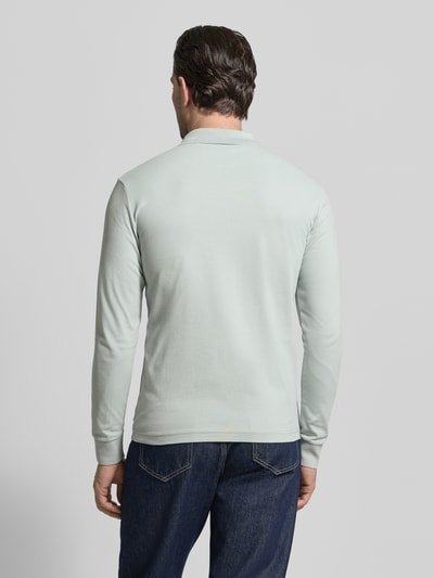 Männermodel trägt Slim Fit Poloshirt aus Baumwoll-Mix Modell 'PASSERBY' von BOSS Orange in Unifarbe, Piqué-Textur, Ganzkörperansicht Rückansicht.