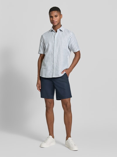 Männermodel trägt Slim Fit Business Hemd aus Leinen-Misch mit Kentkragen von Jake*s, blau-weiß gestreift, Kurzarm, Ganzkörperansicht von vorne.