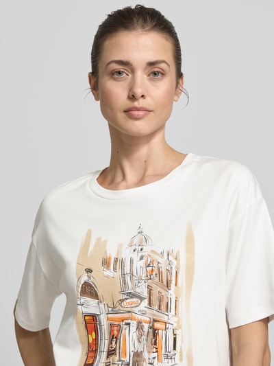 Frauenmodel trägt T-Shirt mit Motiv-Print und Strasssteinbesatz von monari, Reine Baumwolle, Lockerer-Schnitt, Rundhalsausschnitt, Nahaufnahme Oberkörper.