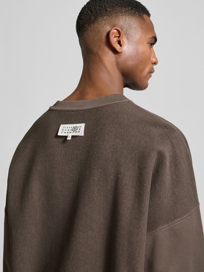 Männermodel trägt Oversized Sweatshirt mit Logo-Print von MM6 Maison Margiela in Braun aus reiner Baumwolle, Detailaufnahme Rückenansicht.