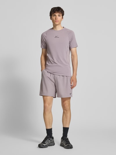 Mannenmodel draagt Shorts mit Logo-Print und Eingrifftaschen van NIKE TRAINING in lichtpaars, recht model, steekzakken, trekkoord, logoprint, maat M bandwijdte 41 cm, binnenbeenlengte 19 cm, ganzkörperansicht van voren.