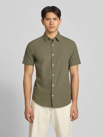 Männermodel trägt Regular Fit Freizeithemd aus Baumwoll-Leinen-Mix von Jack & Jones in Olivgrün, Knopfleiste, Kentkragen, Ganzkörperansicht von vorne.