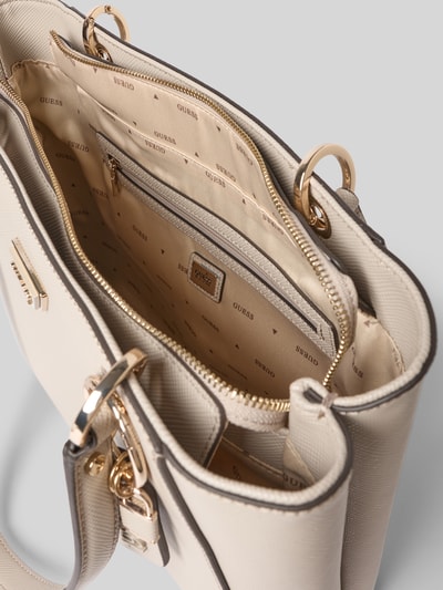 Produktfoto, cremefarbene Umhängetasche mit Label-Applikation Modell 'NOELLE II' von Guess, Hauptfach mit Reißverschluss, Innenfach mit Reißverschluss, Tragehenkel, 38 cm Breite, 27 cm Länge, 10 cm Tiefe, 58 cm Schulterriemen, glatte und strukturierte Oberfläche, goldfarbene Details