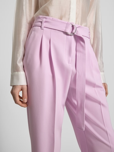 Frauenmodel trägt Regular Fit Schmale Hose mit Gürtel Modell 'TAPIAH' von BOSS in Unifarbe Rosa, High Waist, Bügelfalten, Nahaufnahme Oberkörper.
