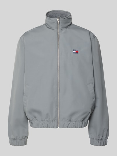 Produktfoto, Regular Fit Bomberjacke mit Label Stitching von Tommy Jeans in Optik: Unifarben, Stehkragen, Reißverschluss, Langarm, elastischer Ärmelabschluss, elastischer Rumpfabschluss, Innentasche, Eingrifftaschen mit Druckknopf, glatte Oberfläche, kühles Grau.