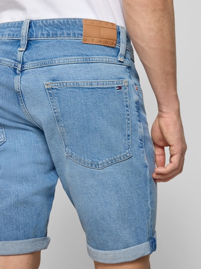 Männermodel trägt Regular Fit Jeansshorts aus Baumwoll-Mix Modell 'RONNIE SHORT' von Tommy Jeans in Denim-Optik mit Label-Patch, 5-Pocket-Design, Ganzkörperansicht Rückansicht.