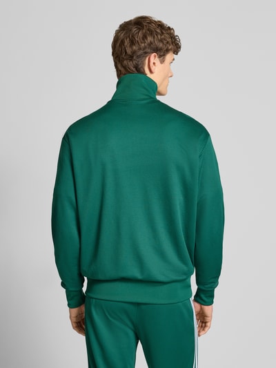 Mężczyzna nosi Trainingsjacke mit Stehkragen von adidas Originals w kolorze zielonym, krój regular fit, widok całej sylwetki z tyłu