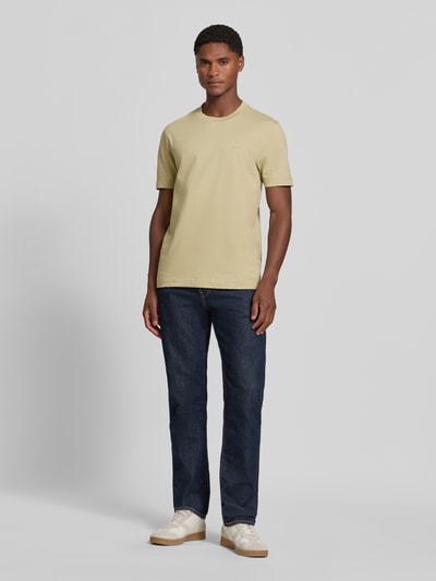 Männermodel trägt Regular Fit T-Shirt aus reiner Baumwolle Modell 'Thompson' von BOSS in Beige, kombiniert mit Jeans; Ganzkörperansicht von vorne. Herren T-Shirt von BOSS