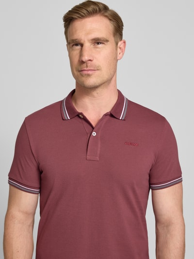Mężczyznamodel nosi Slim Fit Poloshirt mit Kontraststreifen od Geox, mieszanka bawełny, kołnierzyk polo, krótka listwa guzikowa, paski w kontrastowym kolorze, długość tyłu w rozmiarze M 69 cm, zbliżenie na górną część ciała.