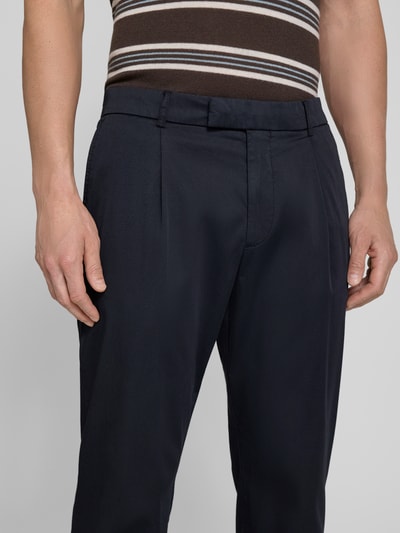 Mężczyzna nosi Anzughose mit Biesen und französischen Eingrifftaschen von CINQUE, mieszanka bawełny z dodatkiem streczu, krój straight fit, zaszewki, wpuszczane kieszenie, guziki, zamek błyskawiczny, szerokość w rozmiarze 50: 48 cm, długość wewnętrzna nogawki: 76 cm, ciemny kolor, gładka tekstura, zbliżenie na górną część nóg, widok z przodu
