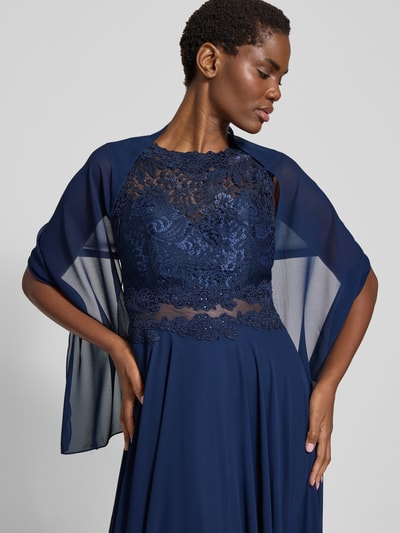 Frauenmodel trägt Abendkleid mit floralen Stickereien von Mascara in Dunkelblau, taillierte Passform, ärmellos, transparente Einsätze, wattierte Cups, mehrlagiger Rockteil, Reißverschluss am Rücken, Rückenlänge 153 cm, Brustweite 36 cm, Nahaufnahme Oberkörper.