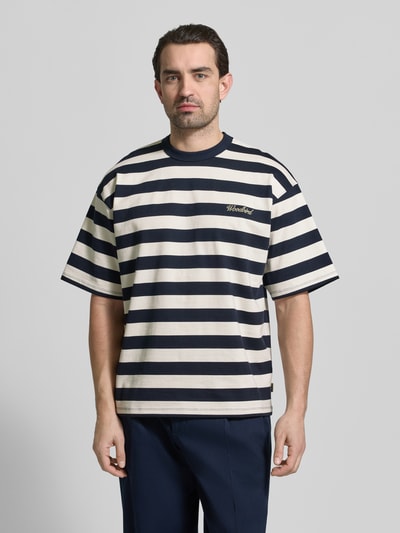 Männermodel trägt Relaxed Fit T-Shirt mit Logo-Stitching Modell 'Beam' von Woodbird aus reiner Baumwolle, Rundhalsausschnitt, Ganzkörperansicht von vorne.