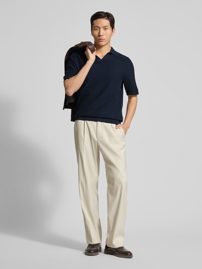 Männermodel trägt Regular Fit Poloshirt aus reiner Baumwolle von Tom Tailor in dunkelblauer Strickoptik mit V-Ausschnitt, Ganzkörperansicht von vorne
