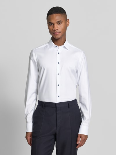Męski model nosi Slim Fit Freizeithemd mit Kentkragen od OLYMP Level Five, biały, długi rękaw, krój slim fit, bawełniany elastyczny materiał, widoczne mankiety sportowe, guzikowa listwa, widok całej sylwetki z przodu. Długość pleców w rozmiarze 40: 80 cm, szerokość ramion w rozmiarze 40: 44 cm, długość rękawa w rozmiarze 40: 68 cm.