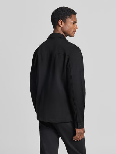Männermodel trägt Slim Fit Hemdjacke mit Viskose-Anteil von Lindbergh in Schwarz, glatte Textur, Ganzkörperansicht Rückansicht. Elastischer Material-Mix, Umlegekragen, durchgehende Knopfleiste, aufgesetzte Brusttasche, Eingrifftaschen, Rückenlänge bei Größe M 70 cm.