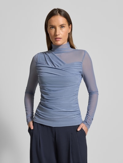 Frauenmodel trägt Slim Fit Langarmshirt aus semitransparentem Mesh Modell 'C_ETULAH' von BOSS Orange, Optik: Unifarben, Wickeloptik, hochgeschlossen, Ärmelform: Langarm, Ärmelabschluss und Rumpfabschluss offen, Materialverarbeitung: Mesh, in hellem Blau, dezente Faltenstruktur. Nahaufnahme Oberkörper.