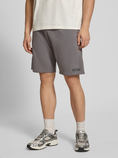 Männermodel trägt Regular Fit Shorts mit Label-Stitching von REVIEW in Grau aus Baumwoll-Mix, elastischer Bund, Nahaufnahme Oberkörper.