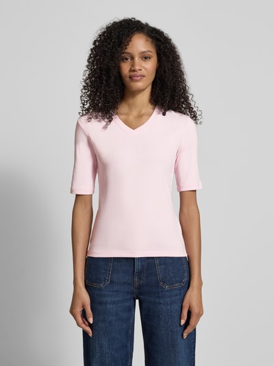 Modelka nosi T-shirt mit V-Ausschnitt von Christian Berg Woman z mieszanki bawełny i elastanu, krój regular fit, dekolt w serek, rękaw o dł. 1/2, długość tyłu w rozmiarze S: 55 cm, jasnoróżowy, gładki materiał, widok całej sylwetki z przodu.