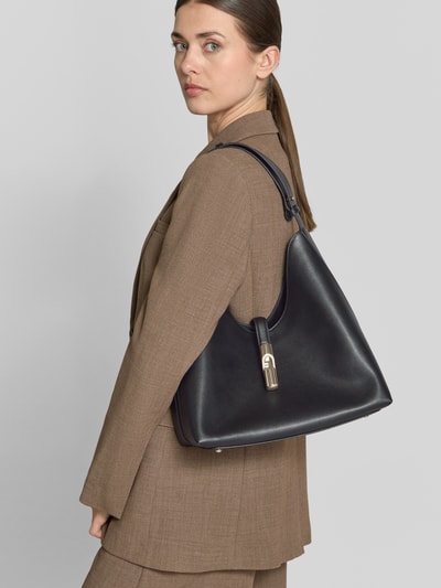 Kobiece modelka nosi czarną Handtasche mit Tragehenkel Modell 'GOCCIA' od FURLA, gładka tekstura, damska torebka, Szerokość w rozmiarze 1: 28 cm, długość 30 cm, głębokość 16 cm, długość paska na ramię 50 cm, z zamykaną kieszenią wewnętrzną, widok na cały korpus z przodu.