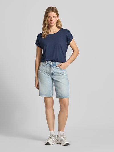 Kobiece modelka nosi damski t-shirt o kroju regular fit z mieszanki wiskozy, model 'MOSTER' od Only, granatowy, jasnoniebieskie szorty, białe skarpetki i sneakersy, damski t-shirt od Only, pełny widok z przodu.