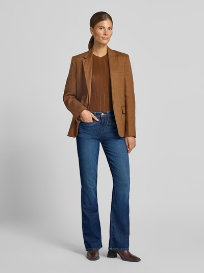 Modelka kobieca nosi niebieskie jeansy bootcut z bawełnianego miksu Bootcut-Jeans aus Baumwoll-Mix Modell 'SHAKIRA' od Brax, brązową marynarkę i sweter, wykończenie matowe, damskie jeansy bootcut od Brax, pełny widok z przodu.