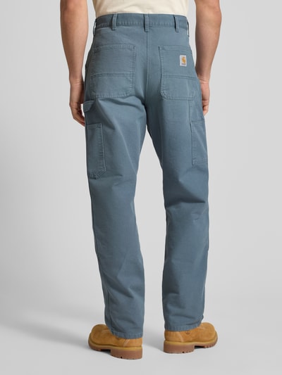 Mężczyzna nosi spodnie Hose mit Eingrifftaschen Modell 'Dearbor' od Carhartt Work In Progress z czystej bawełny, krój regular fit, kolor niebieski, szerokość w rozmiarze 32/32: 46 cm, długość nogawki od kroku 80 cm, widok całej sylwetki z tyłu.