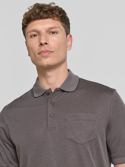 Männermodel trägt Regular Fit Poloshirt mit Brusttasche und Label-Stitching von bugatti in Grau, feine Struktur, Nahaufnahme Oberkörper.