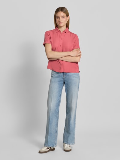 Modelka kobieca nosi Regular Fit Hemdbluse mit 1/2-Arm od Jake*s Casual z mieszanki wiskozy, kolor różowy, klasyczny kołnierzyk kent, zapięcie na guziki, krój regular fit, długość tyłu w rozmiarze 36 to 62 cm, długość rękawa 21 cm, do tego jasnoniebieskie dżinsy, białe sneakersy, tło jasnoszare, widoczne miękkie tekstury tkaniny, widok całej sylwetki z przodu.
