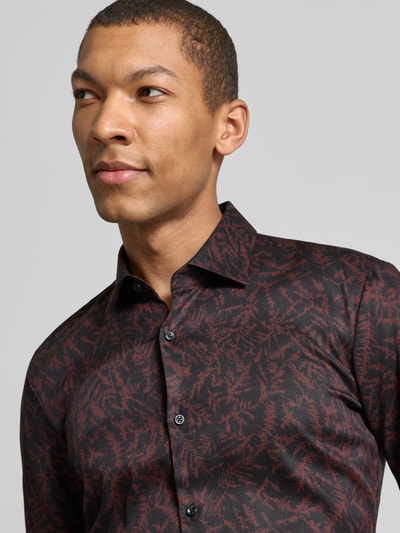 Männermodel trägt Slim Fit Businesshemd aus Lyocell Modell 'KENNO' von HUGO mit Allover-Muster in Rot und Schwarz, Nahaufnahme Oberkörper.