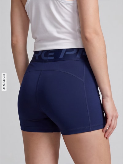 Frauenmodel trägt dunkelblaue, eng anliegende Sportshorts mit Dri-FIT-Technologie Modell 'Pro Sculpt' von Nike, Damen Sportshorts von Nike Training, Ganzkörperansicht Rückansicht, KI-modifiziertes Bild.