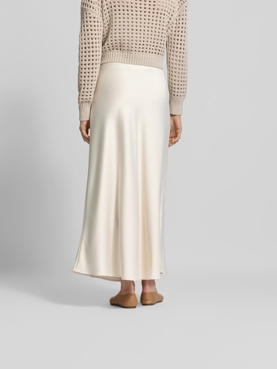 Frauenmodel trägt Maxirock mit Reißverschluss aus Satin von Juvia in Creme, schmale Passform, glatte Textur, Maxi-Länge, Ganzkörperansicht Rückansicht.