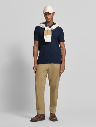 Männermodel trägt Regular Fit Poloshirt aus reiner Baumwolle von Barbour in Optik: Unifarben, Materialverarbeitung: Piqué, Ganzkörperansicht von vorne.