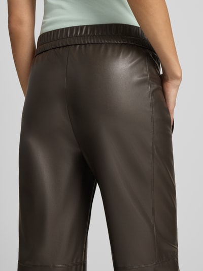 Frauenmodel trägt Tapered Fit Hose in Leder-Optik von Marc Cain, braun, elastischer Bund, Eingrifftaschen, Detailaufnahme Rückansicht.