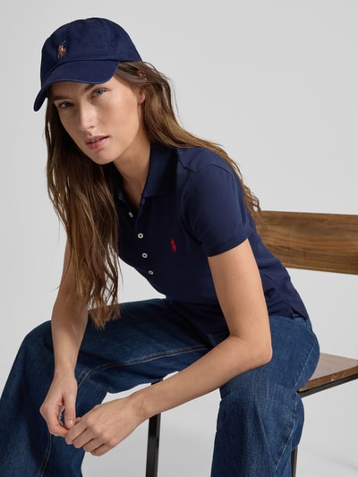 Kobiece model prezentuje Slim Fit Koszulkę polo z wyhaftowanym logo Model 'JULIE' od Polo Ralph Lauren z mieszanki bawełny i elastanu, jednokolorowy design, kołnierzyk polo, krótka listwa guzikowa, prążkowane zakończenia rękawów, długość tyłu przy rozmiarze S: 65 cm, jednolity granatowy kolor, gładka faktura, całkowity widok z przodu.