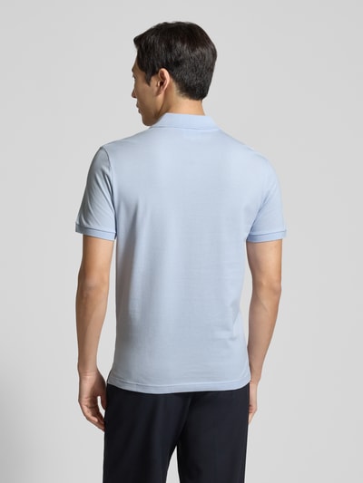 Männermodel trägt Slim Fit Poloshirt aus reiner Baumwolle von Lacoste in hellblau, unifarben, Piqué-Struktur, Ganzkörperansicht Rückansicht.