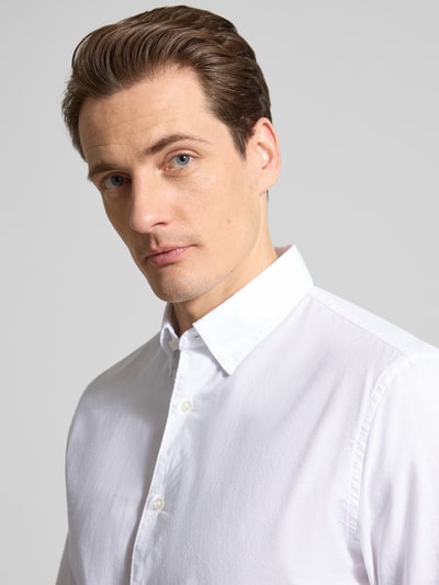 Männermodel trägt Slim Fit Freizeithemd aus reiner Baumwolle von MCNEAL in Weiß, Button-Down-Kragen, Nahaufnahme Oberkörper.