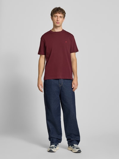 Männermodel trägt Regular Fit T-Shirt aus reiner Baumwolle von Replay in Dunkelrot, lockere Jeans, Ganzkörperansicht von vorne. Herren T-Shirt von Replay, Rundhalsausschnitt, Label-Stickerei, Rückenlänge bei Größe M: 74 cm.
