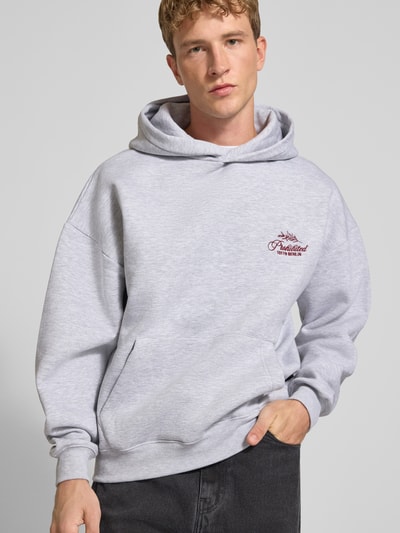 Männermodel trägt Relaxed Fit Hoodie aus Baumwoll-Mix mit Label-Stitching von PROHIBITED in Hellgrau, Känguru-Tasche, Nahaufnahme Oberkörper.